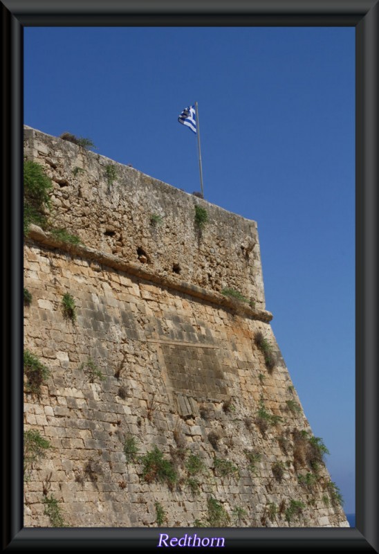 Bandera griega ondeando en los muros de la fortaleza veneciana